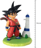 Figura infantil de Son Goku con bastón y cola, acompañada de torre en base